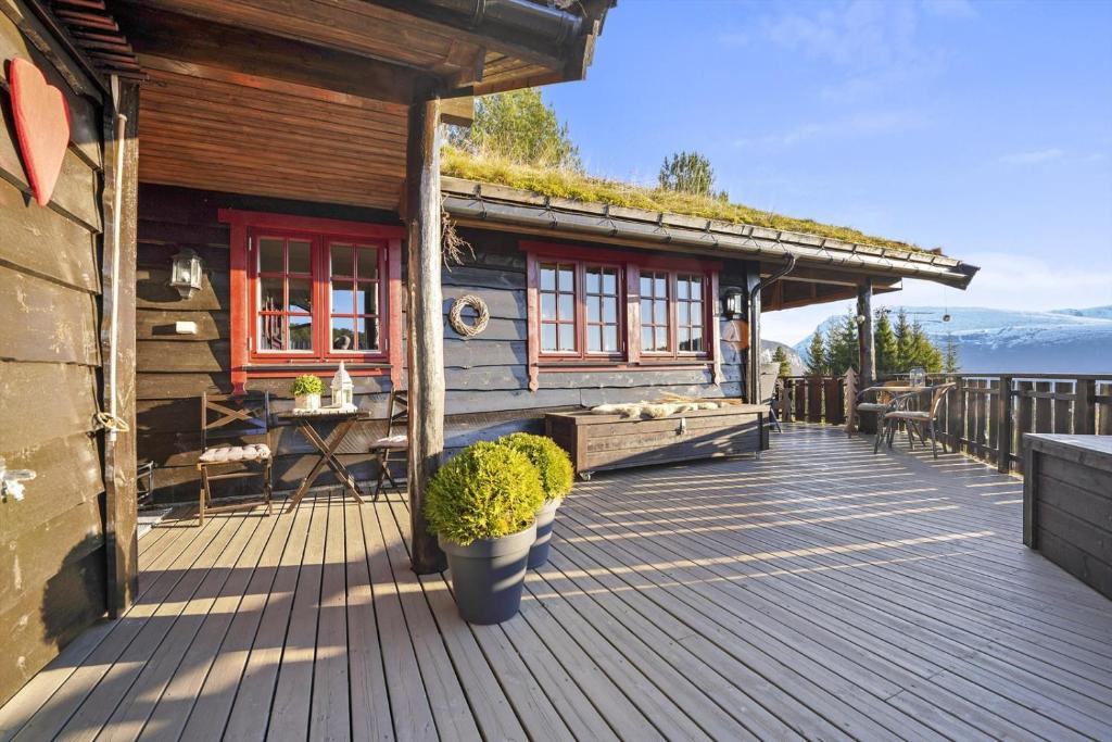 una terraza de madera con una cabaña con techo de hierba en Hytte Stryn skisenter, en Stryn