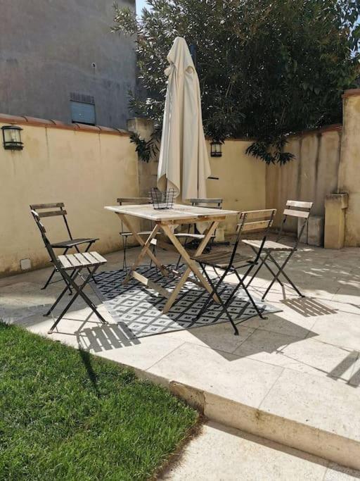 une table avec un parasol, deux chaises et une table dans l'établissement Molinas agréable maison 2 chambres climatisation avec jardin et parking, à Avignon