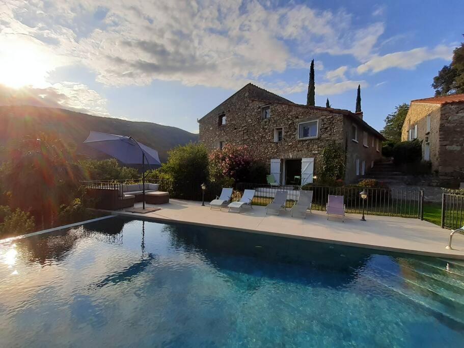 a house with a swimming pool in front of a house at Private apartment within 15th century farmhouse in Arles-sur-Tech