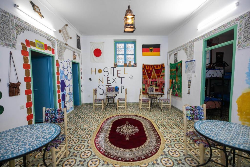 una habitación con mesas y sillas y una alfombra en el suelo en BackHome Fez, en Fez