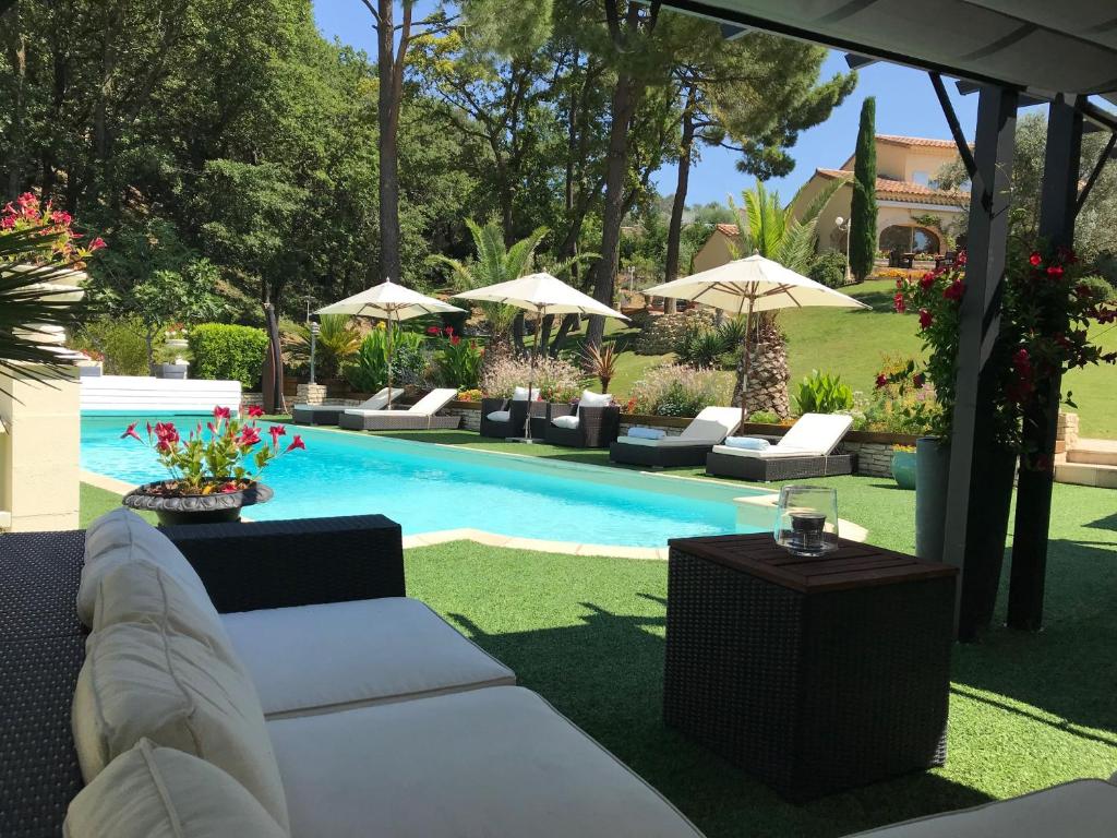 - une piscine avec des canapés et des parasols dans une cour dans l'établissement Le Mas de l'Alliance - 12 p - Air Cond - private Pool - near Grignan, à Roussas