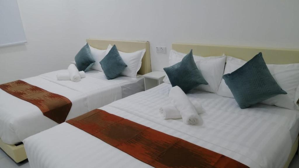 two beds with blue and white pillows in a room at SKYN SMART HOME in Ipoh