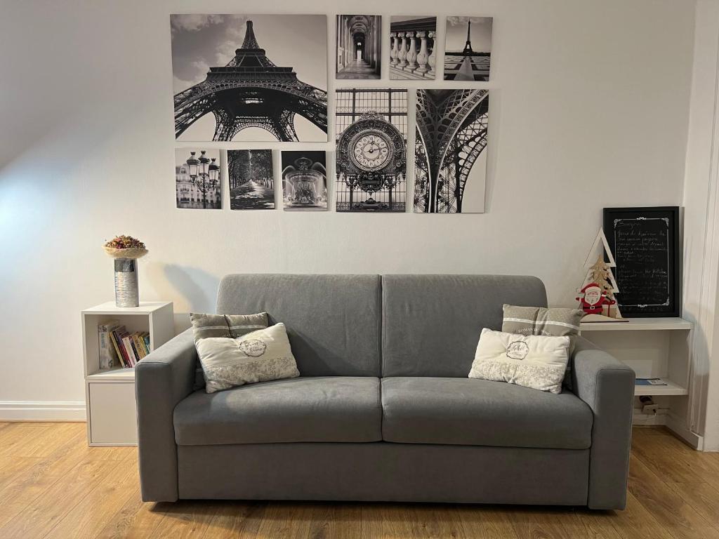 - un canapé dans le salon avec des photos sur le mur dans l'établissement La perle d'Alesia, à Paris