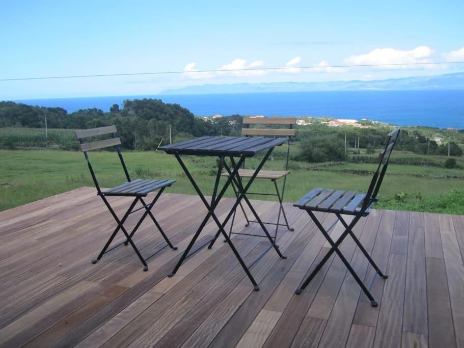 a picnic table and two chairs on a deck at Casa dos Vimes - mar e céu in São Roque do Pico