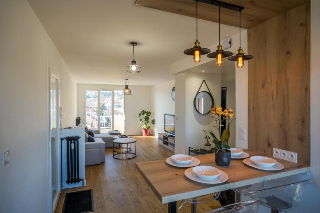 een keuken en een woonkamer met een tafel met borden erop bij Appartement vue montagnes in Gap