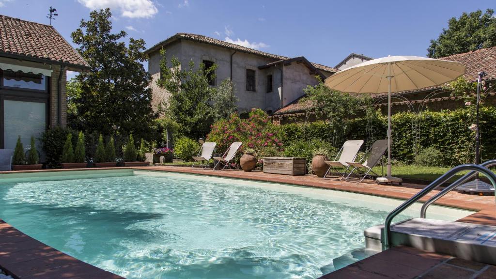 uma grande piscina com guarda-sol e cadeiras em La Locanda di Sant'Anna em Truccazzano