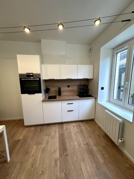 an empty kitchen with white cabinets and a window at Maison fraichement rénové in Lille
