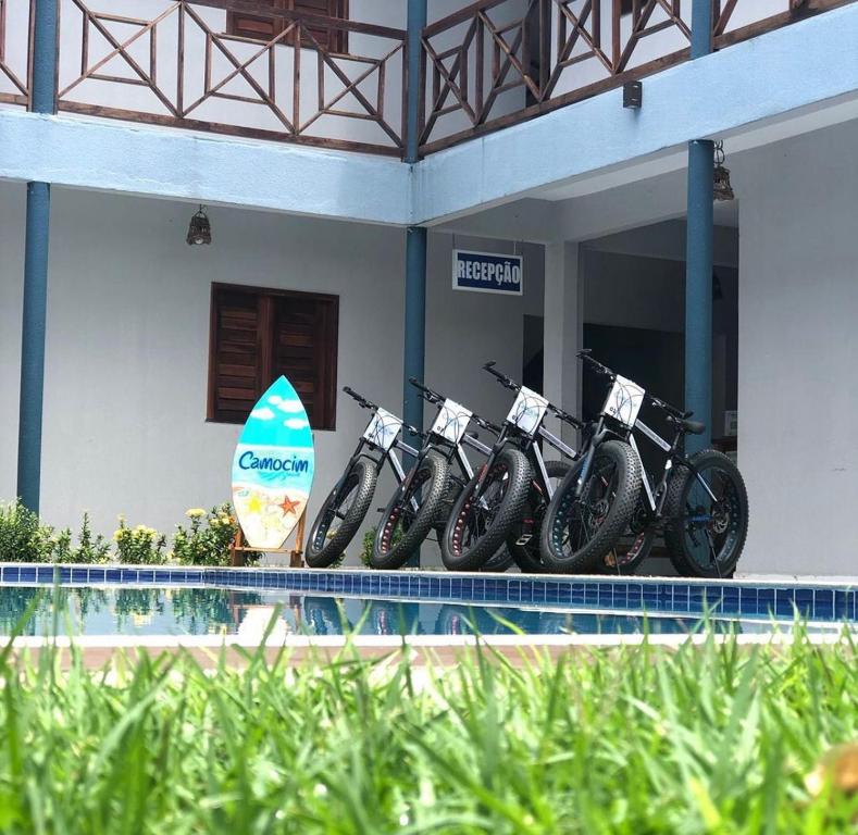 una fila de motocicletas estacionadas al lado de un edificio con una tabla de surf en Pousada Grand Fortim, en Camocim