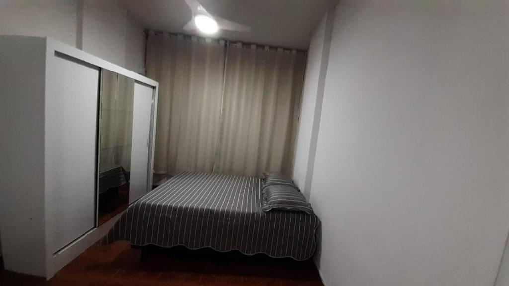 um pequeno quarto com uma cama e um espelho em studio no Rio de Janeiro