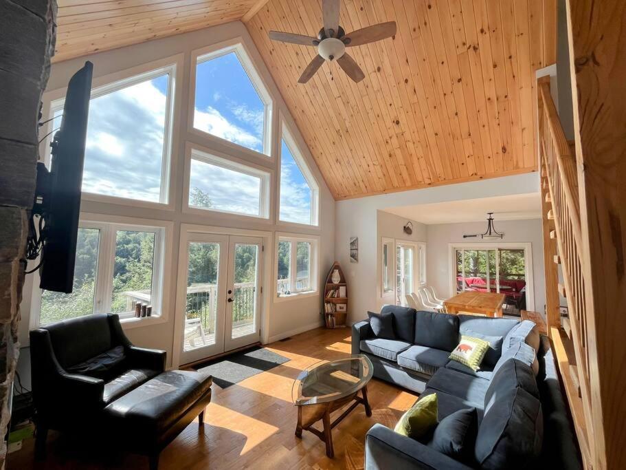 a living room with couches and a ceiling fan at The Bear Cave Cottage at Little Kennisis Lake in Algonquin Highlands