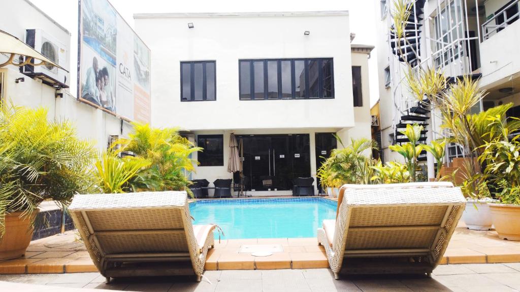 two chairs and a swimming pool in a building at Cata Apartment Hotel And Spa in Ikeja