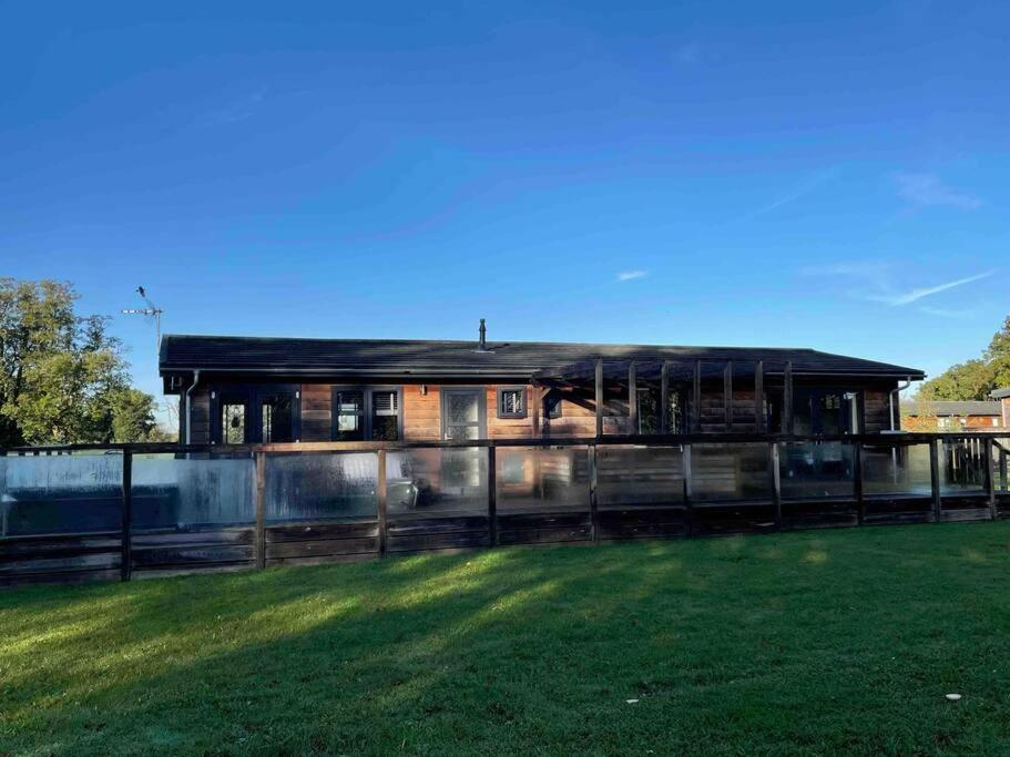 a house with a fence in front of a field at Lush Lodge 