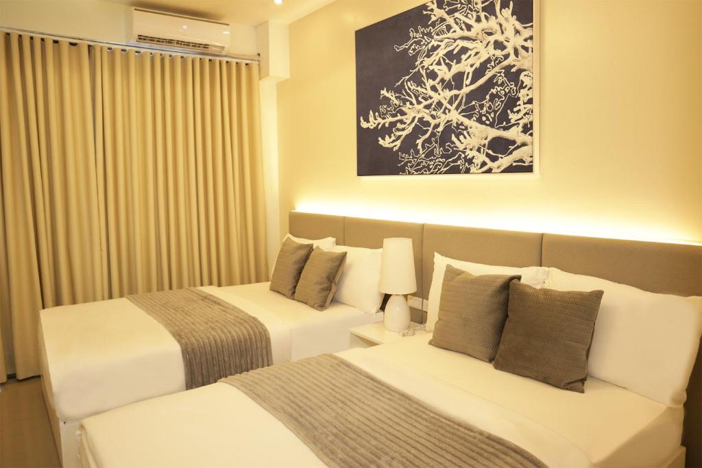 a hotel room with two beds and a painting at Homefort iHotel at Shore Residences in Manila