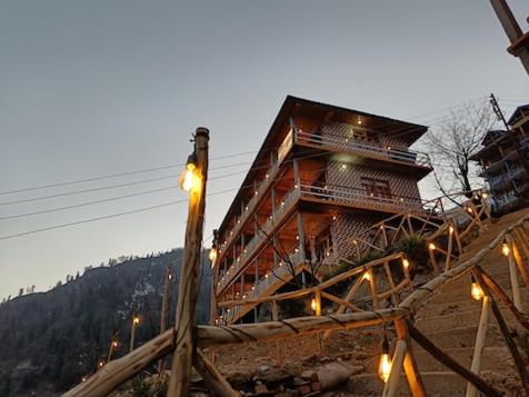 Tosh的住宿－Pahadi Bliss Hostel ,Tosh，山上的木结构建筑,上面有灯
