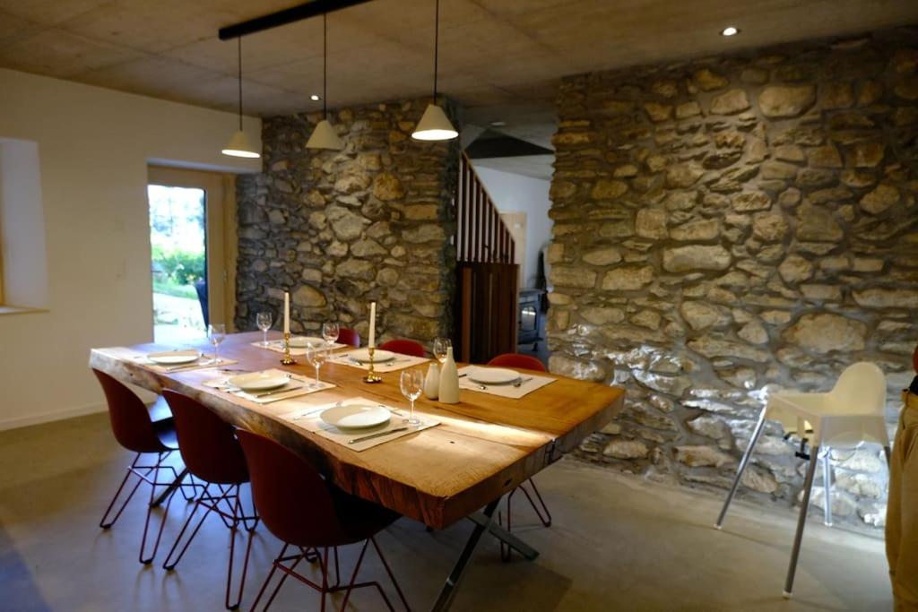 Una gran mesa de madera en una habitación con una pared de piedra. en Maisonnette de campagne en Sion