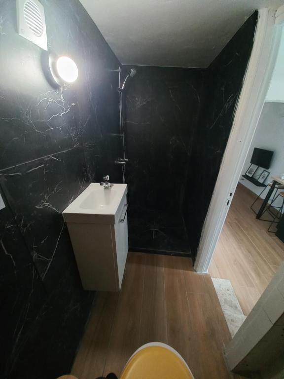 La salle de bains est pourvue d'un lavabo blanc et d'un mur noir. dans l'établissement Le Cosy de Vendargues, à Vendargues