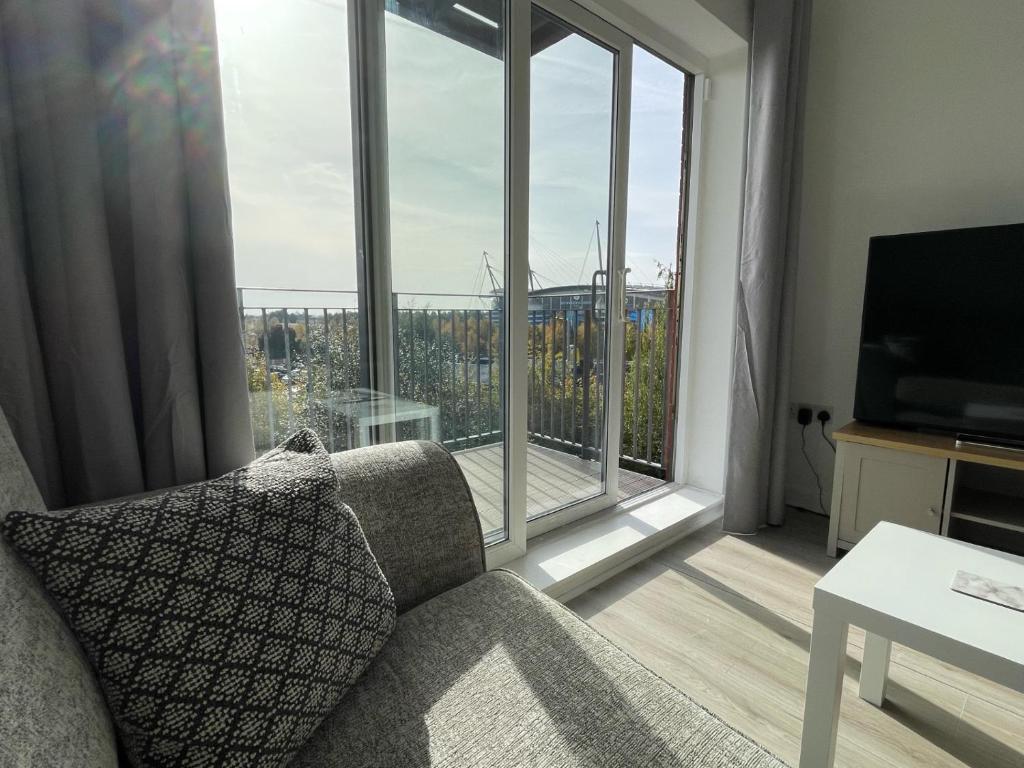 a living room with a couch and a large window at Balcony Apartment - Views Of Etihad Stadium - Near CoOp Live Arena in Manchester