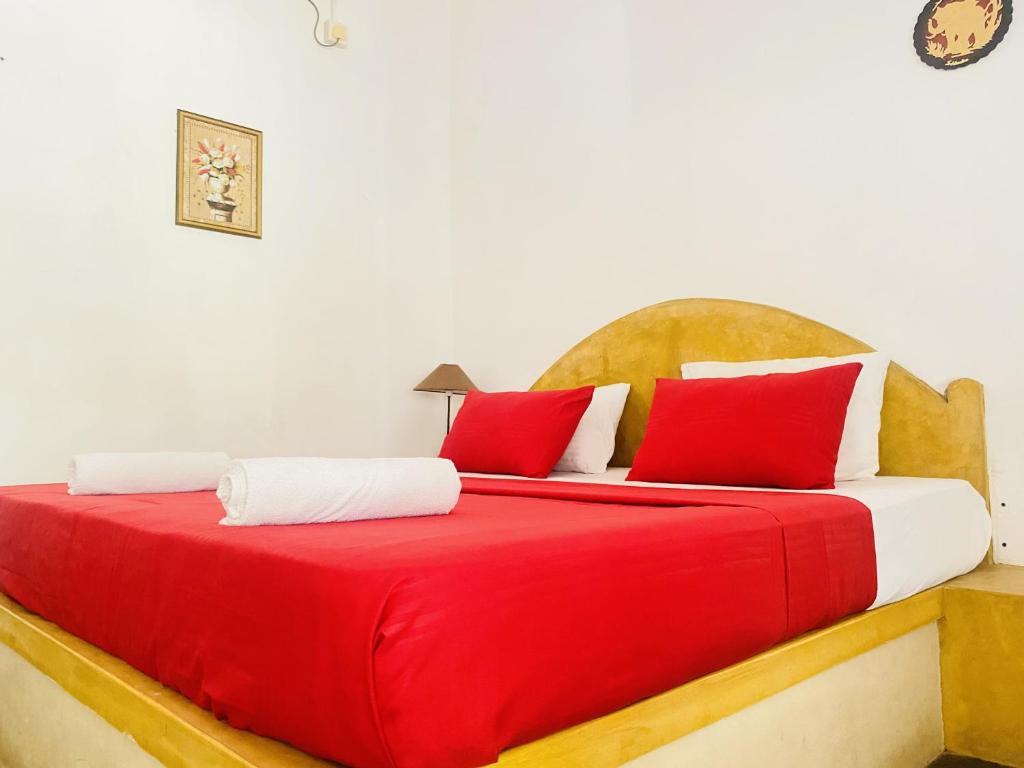 Una cama con almohadas rojas y blancas. en Harmony Beach Hotel, en Arugam Bay