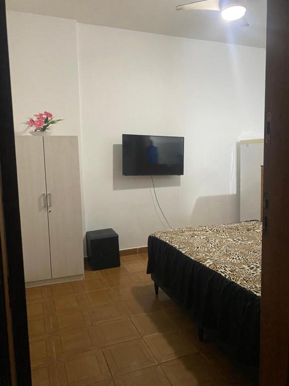 a bedroom with a bed and a tv on the wall at Conjugado Próximo aos Arcos da Lapa e Praia do aterro do Flamengo in Rio de Janeiro