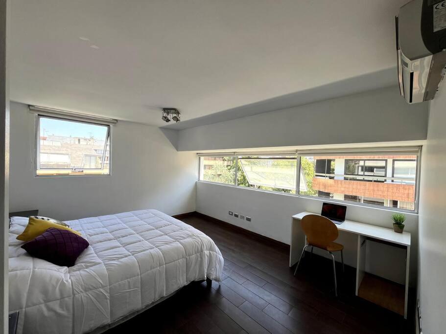 1 dormitorio con 1 cama, escritorio y 2 ventanas en A pasos del Costanera Center! en Santiago