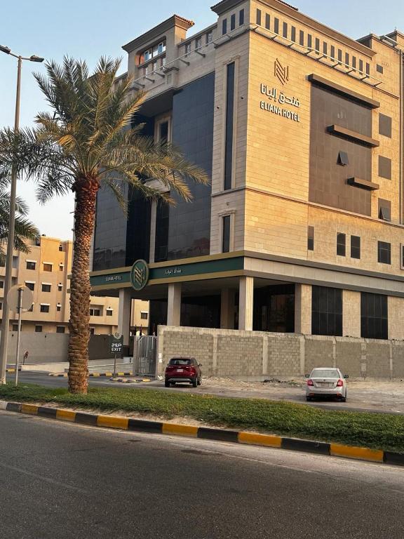 a building with a palm tree in front of a street at Eliana Hotel in Al Khobar