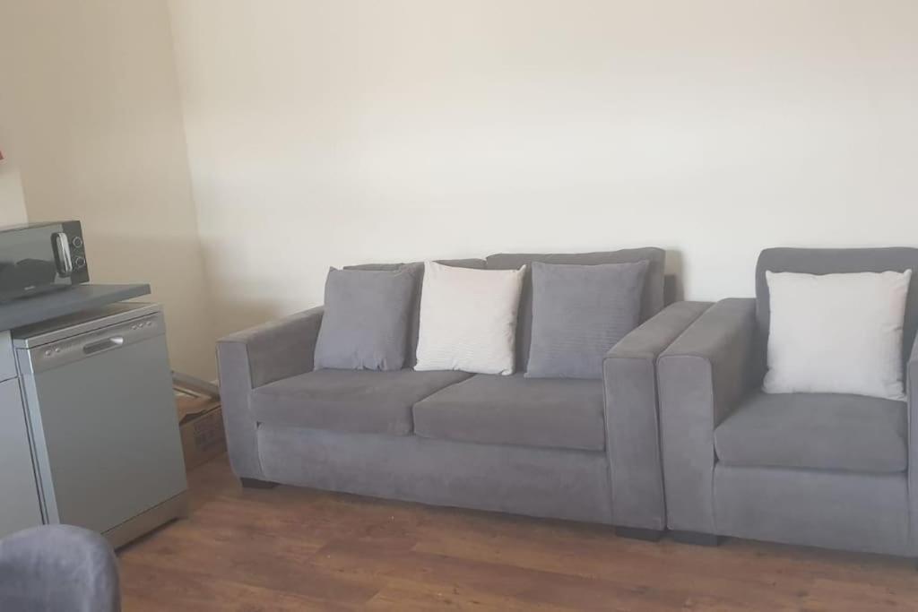 a gray couch with two pillows in a living room at Gravesend 1 Bedroom Flat 2 Min Walk to Station & Town Centre in Kent