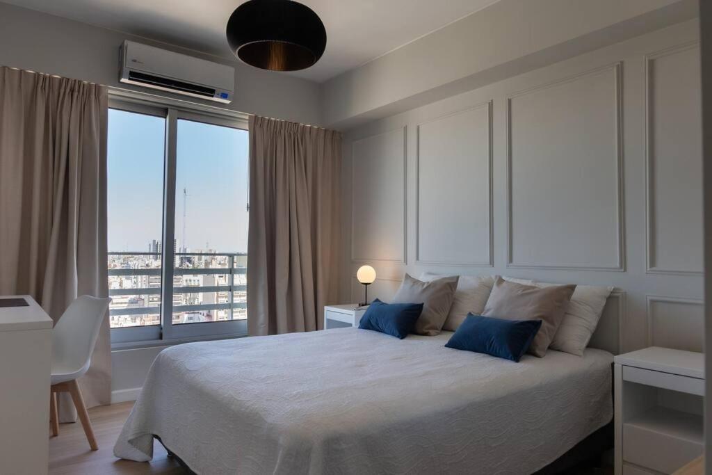 a bedroom with a large white bed with blue pillows at Quartier II by depptö in Buenos Aires