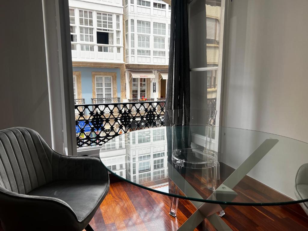 een glazen tafel en stoel in een kamer met een raam bij Oktheway Riego de Agua 23 in A Coruña