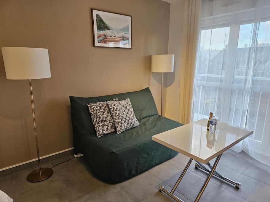 ein Wohnzimmer mit einem grünen Sofa und einem Tisch in der Unterkunft Le Vénitien in Montreuil