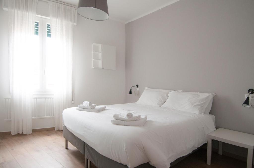 una camera da letto con un letto bianco con due asciugamani di Blanco Apartment - AmbrogioHost a Bologna