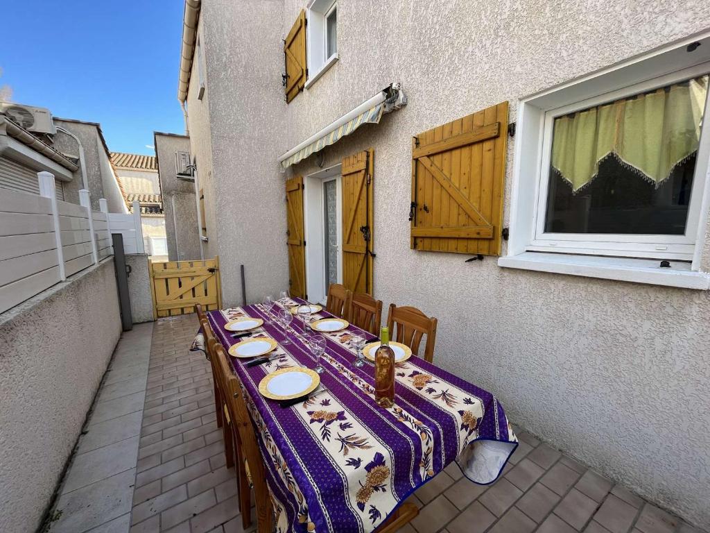 une longue table avec un chiffon de table violet et blanc dans l'établissement Maison de vacances climatisée avec terrasse, parking privé, proche plage et commerces - FR-1-387-190, à Marseillan