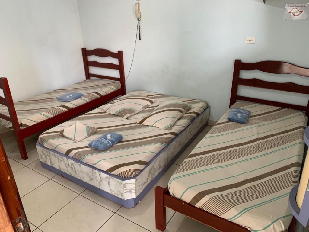 a room with two beds and two chairs at Hotel Vila de São Vicente in São Vicente