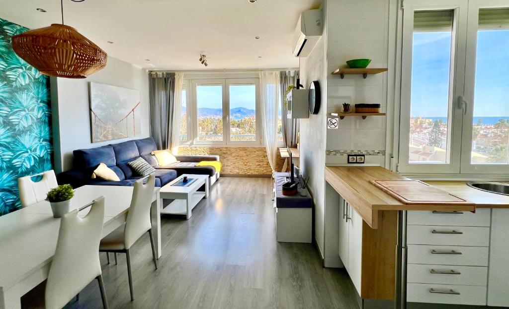 una cucina e un soggiorno con divano blu di Espectacular apartamento junto al mar, con piscina en Málaga a Málaga