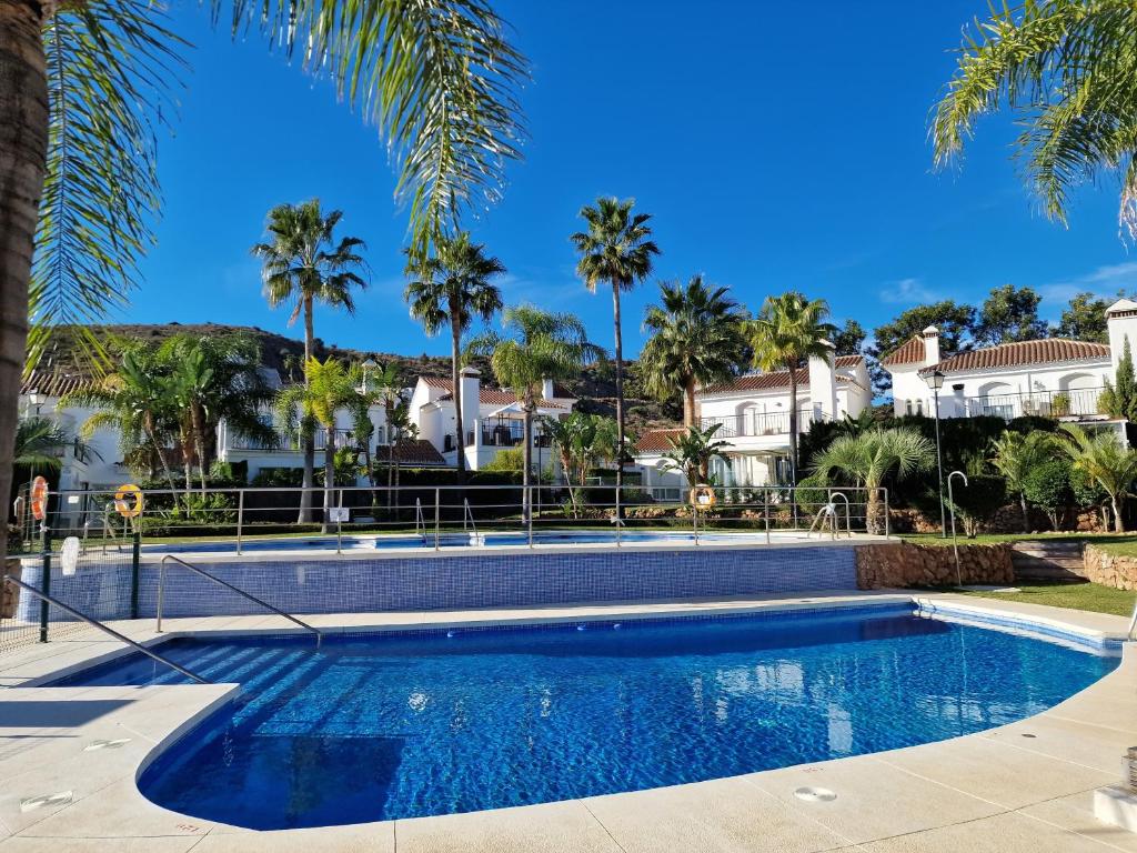 una piscina con palme e case di Sun & Palms - cozy flat in quiet neighbourhood with a great pool area a Málaga