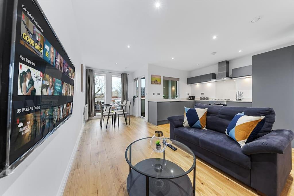 a living room with a blue couch and a kitchen at Luxury Central London Apartments Bermondsey in London