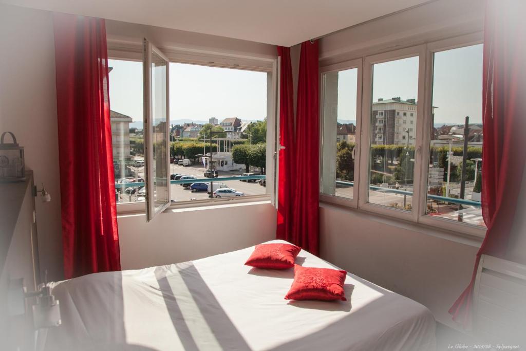 a bed with red pillows in a room with windows at Hôtel Bar le Globe in Saint Die