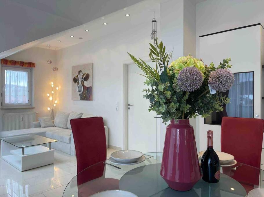 eine Vase mit Blumen auf einem Glastisch im Wohnzimmer in der Unterkunft BERGblume im Zentrum inkl. Staufen PLUS in Oberstaufen