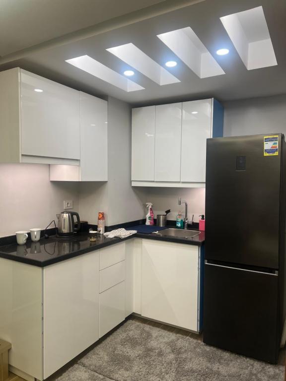 a kitchen with white cabinets and a black refrigerator at Nice Studio on the Roof in Sheikh Zayed