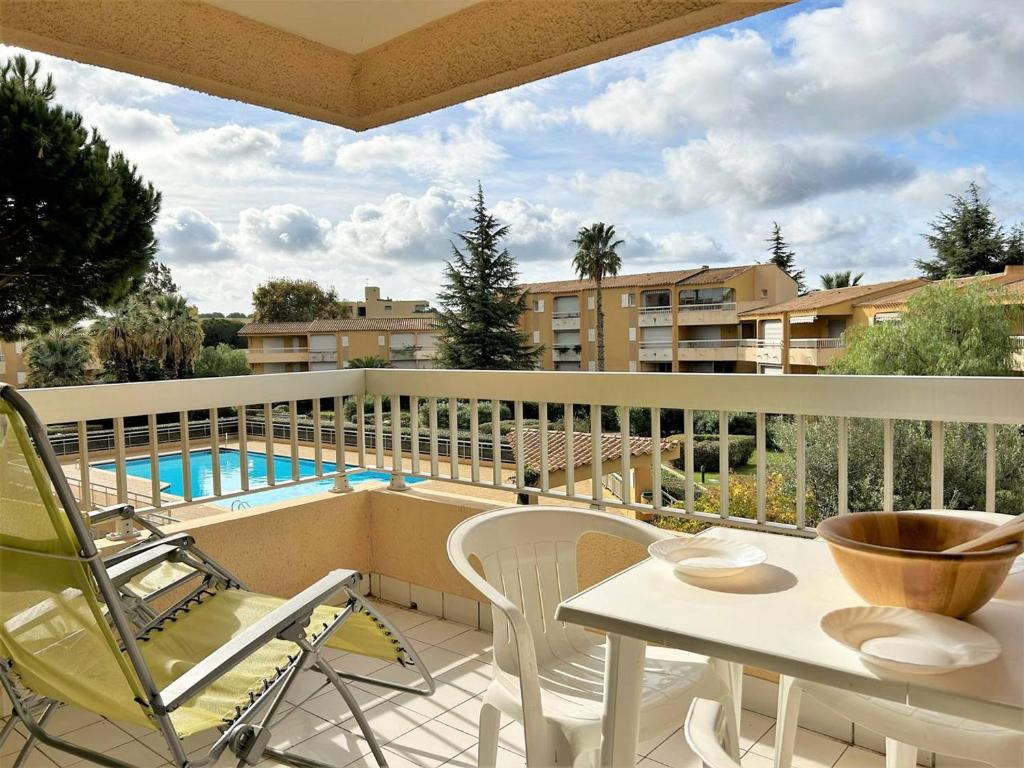 d'un balcon avec une table, des chaises et une piscine. dans l'établissement Studio cabine au Lavandou - 4 couchages, climatisé, balcon, piscine, parking inclus - FR-1-251-480, au Lavandou