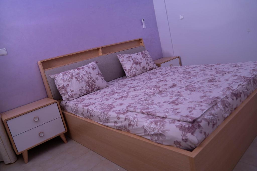 1 dormitorio con cama con marco de madera y almohadas en Immeuble INNA en Ziguinchor