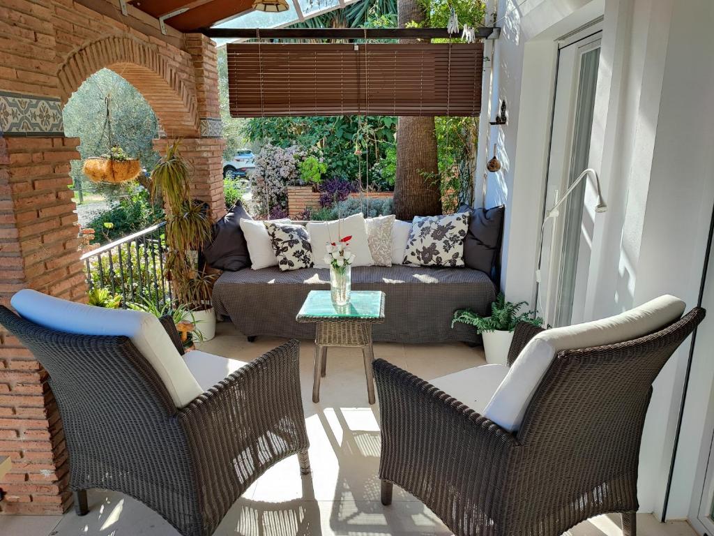 un patio con sofá, sillas y mesa en Garden Apartment, Cortijo Fruitful Hills, en Coín