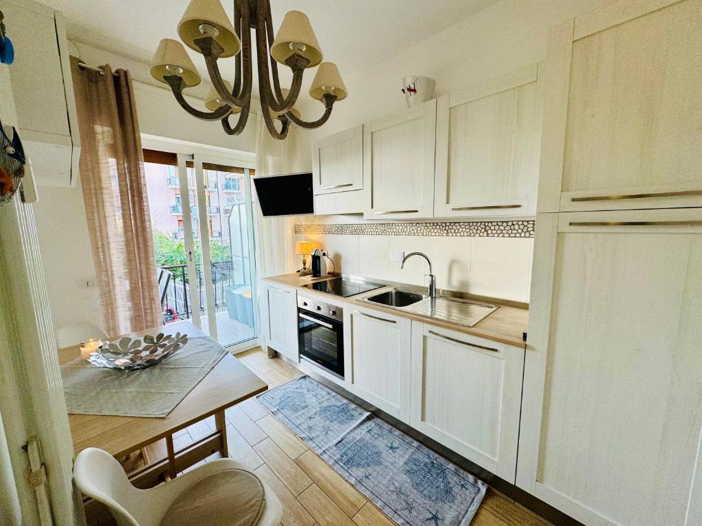 uma cozinha com armários brancos, um lavatório e uma mesa em Il Timone em Riva Ligure