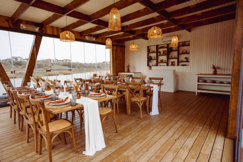 a restaurant with wooden tables and chairs and windows at A-BY THE LAKE - PRIVATE A FRAME VILLAS in Căciulaţi