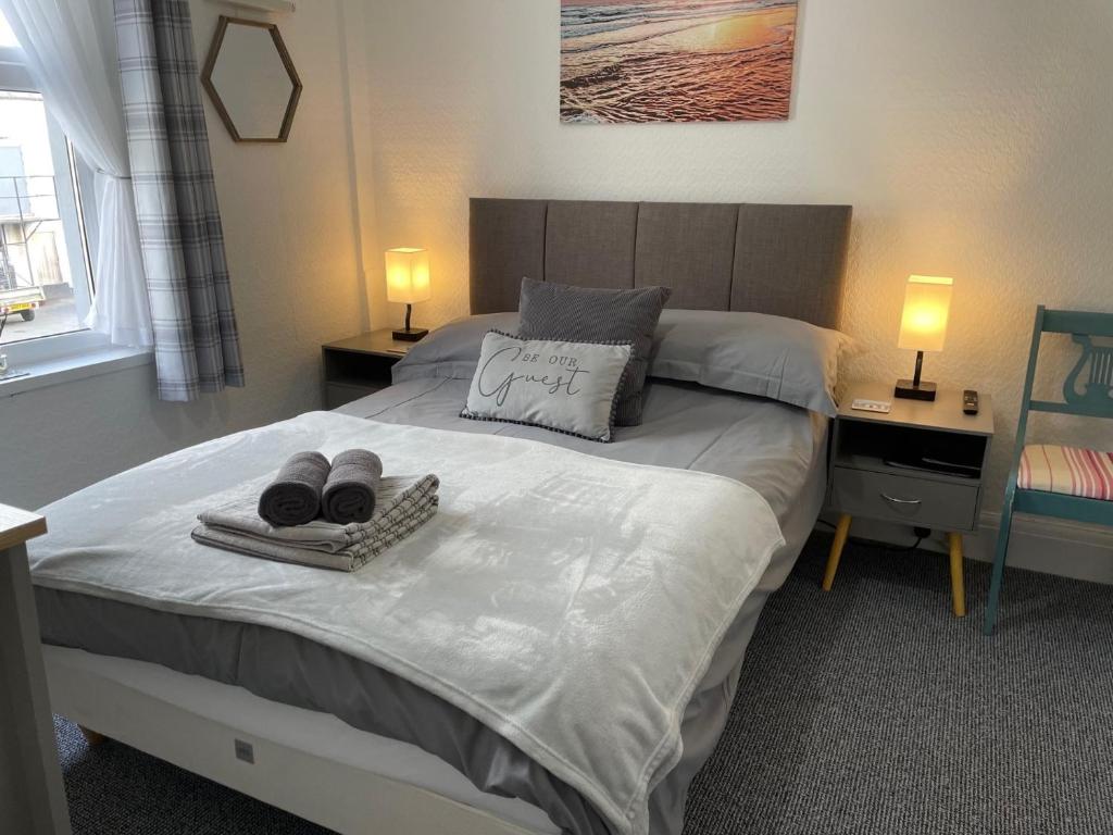 a bedroom with a bed with two towels and two lamps at Bella Vista in Paignton