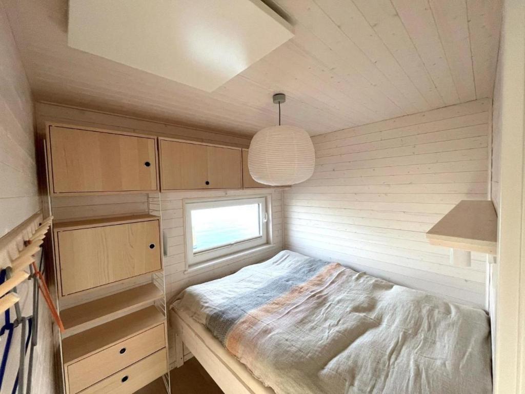 Habitación pequeña con cama y ventana en Hausboot Bruntje mit Dachterrasse in Kragenæs auf Lolland/DK, en Torrig