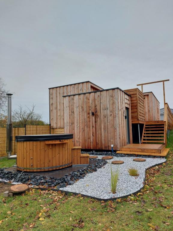 una pequeña casa de madera con una escalera en un patio en Gîte de la Bridolée, sauna et bain nordique, 