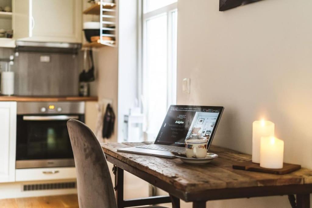 a laptop computer sitting on a wooden table in a kitchen at Hidden gem near the Old Town Bridge, 40m² apt. in Trondheim