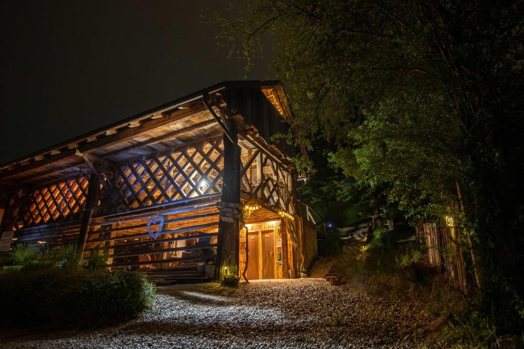 un edificio de madera con luces encendidas por la noche en Hay barn unique experience Visole, en Slovenska Bistrica