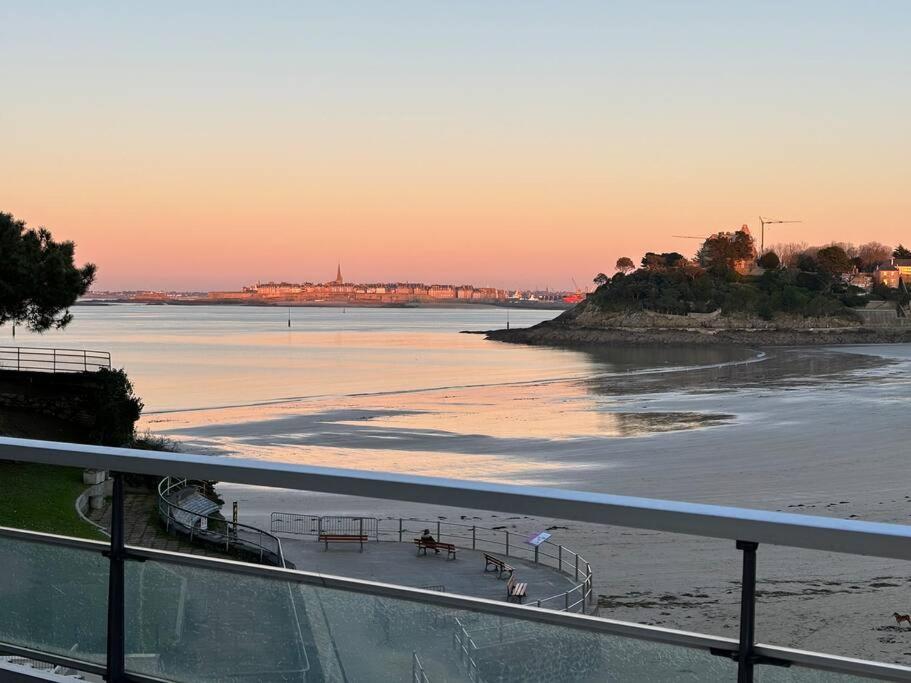 - une vue sur la plage et l'océan au coucher du soleil dans l'établissement Appartement le Cristal Dinard bord de mer, à Dinard