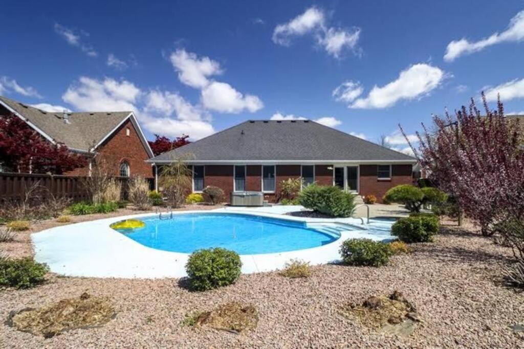 ein Haus mit einem Pool vor einem Haus in der Unterkunft Spacious Derby Home with Hot Tub in Louisville